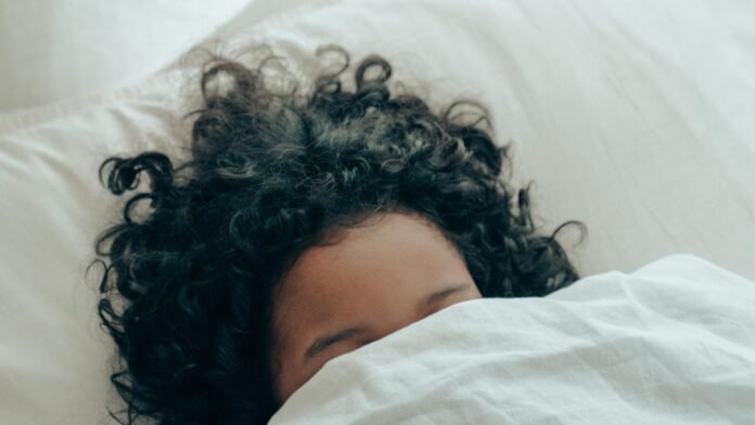 A kid is sleeping peacefully in her favourite white bedding